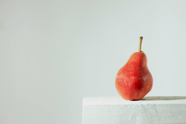 A closeup of a delicious ripe pear on a white surface against a gray background - Foto, Imagen