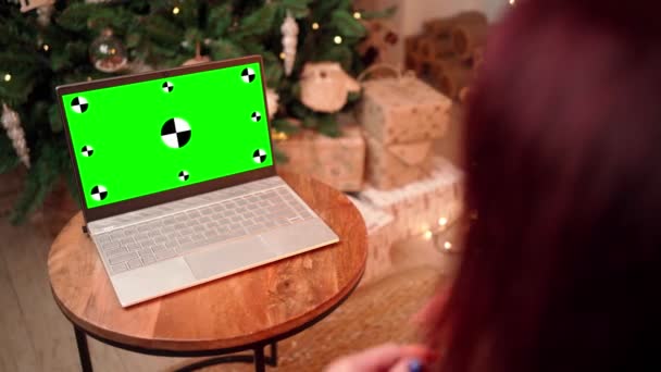 Žena v Vánocích komunikuje na video volání pomocí notebooku se zelenou obrazovkou.  - Záběry, video