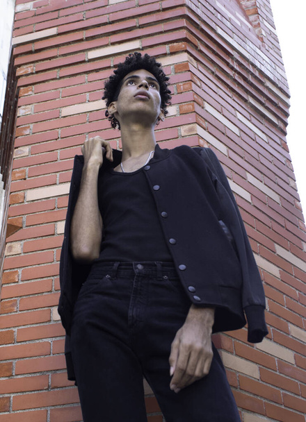 A low angle shot of a Hispanic male in a black outfit posing on the streets in Old Havana, Cuba - 写真・画像