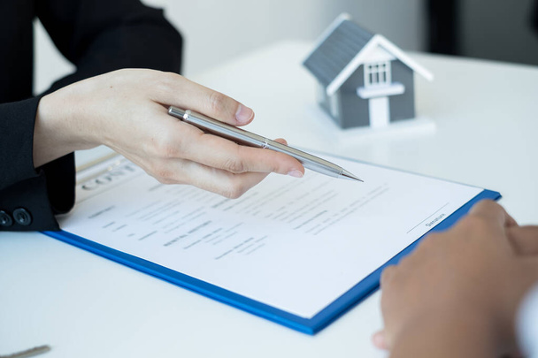 Un agent immobilier avec un modèle de maison parle aux clients de l'achat d'assurance habitation. Concept d'assurance habitation. - Photo, image