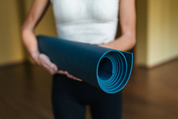  Close-up of a girl holding a blue yoga mat in her hands. - Фото, изображение