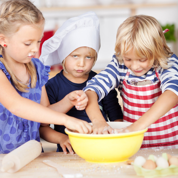 Girl pouting while sisters making dough - Photo, image