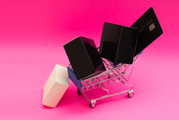ピンクの背景にショッピングカートとギフトボックス - 写真・画像