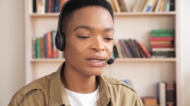 Selbstbewusste schwarze Geschäftsfrau mit Headset, die entfernte Chats von zu Hause aus führt. - Filmmaterial, Video