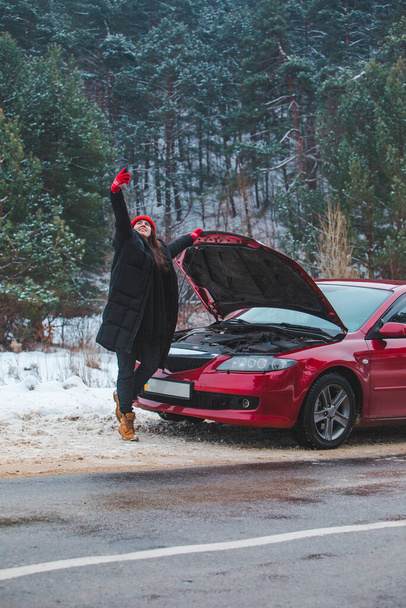 woman calling for help with broken down car at winter highway stopped at roadside - Photo, Image