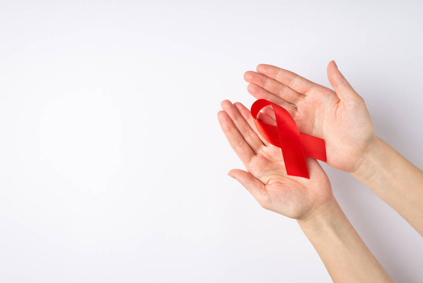 Ego-Draufsicht Foto von weiblichen Händen, die rotes Band in den Handflächen zeigen, Symbol für Hilfsbewußtsein auf isoliertem weißen Hintergrund mit Leerraum - Foto, Bild