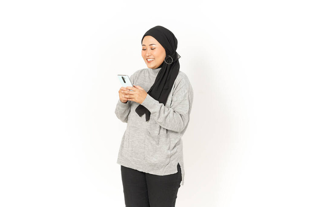 Úsměv a použití Smartphone krásné asijské ženy na sobě hidžáb izolované na bílém pozadí - Fotografie, Obrázek