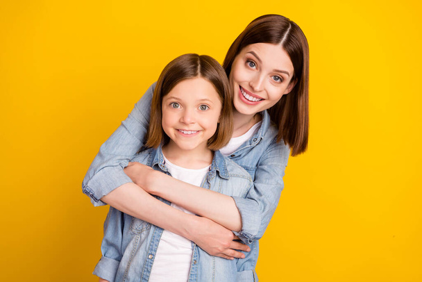 Photo of sweet shiny siblings dressed denim shirts hugging smiling isolated yellow color background. - Фото, изображение