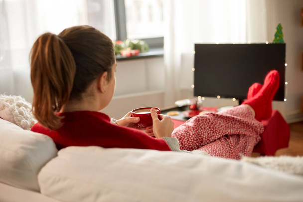 woman watching tv and drinking coffee on christmas - 写真・画像