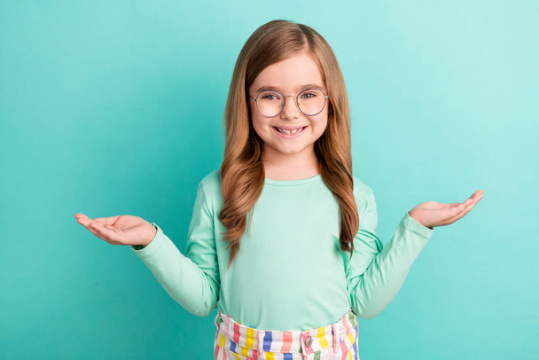 Photo of young little girl happy positive smile hold hands ad pros cons solution decision isolated over teal color background. - Фото, зображення