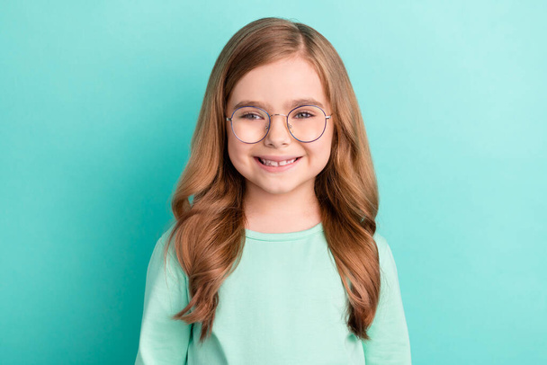 Photo of young cheerful attractive little girl happy positive smile wear eyeglasses isolated over teal color background. - 写真・画像