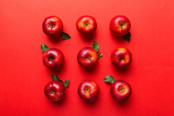 Wiele czerwonych jabłek na kolorowym tle, widok z góry. Jesienny wzór ze świeżym jabłkiem powyżej widoku z miejsca na kopiowanie projektu lub tekstu. - Zdjęcie, obraz