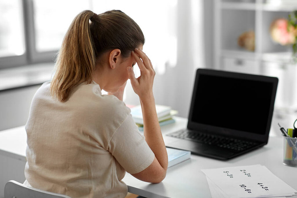 tired teacher with laptop having headache at home - Photo, image