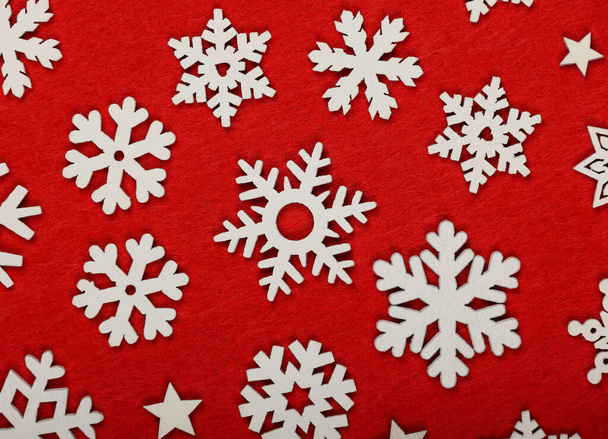 Close up wzór białe drewniane płatki śniegu Świąteczne dekoracje na czerwonym tle filcu, widok na blat stołu, płaskie leżaki - Zdjęcie, obraz