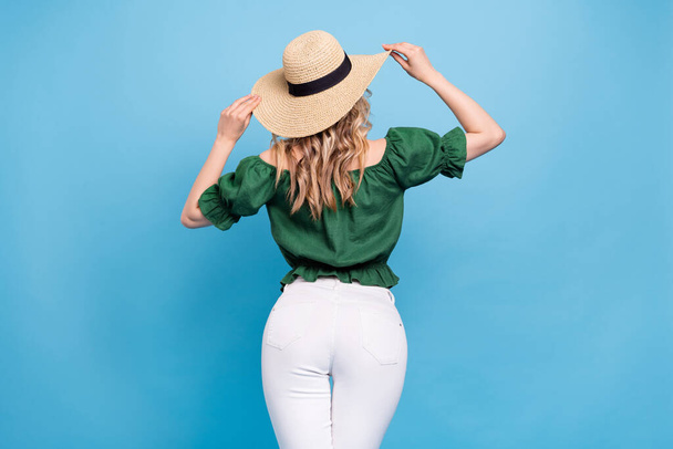 Rear back view photo of tourist lady wear straw hat bear shoulders green blouse pants isolated blue color background. - Фото, изображение