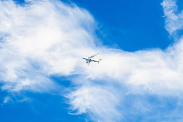 Fehér repülő a kék égen. Felhők a széltől. Fénykép messziről. Repülés egy másik országba. - Fotó, kép