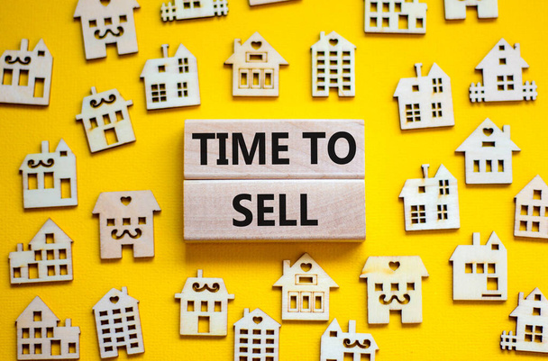Time to sell house symbol. Concept words 'Time to sell' on wooden blocks near miniature houses. Beautiful yellow background, copy space. Business and time to sell house concept. - Foto, Imagem