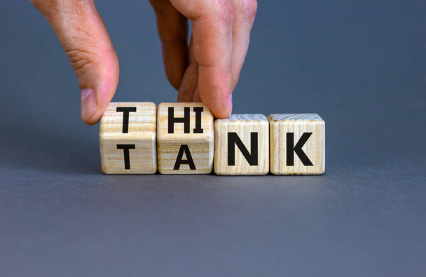 Think tank symbol. Businessman turns wooden cubes and changes the word 'tank' to 'think' or vice versa. Beautiful grey table, grey background, copy space. Business, think tank concept. - Фото, изображение