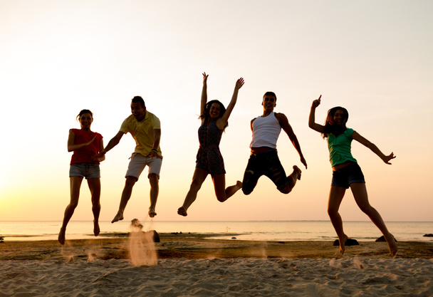 lachende vrienden dansen en springen op strand - Foto, afbeelding