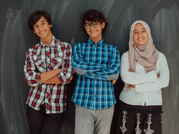 A portrait of a group of Arab teenagers with crossed arms standing in front of a school board . The concept of modern and successful education - Φωτογραφία, εικόνα
