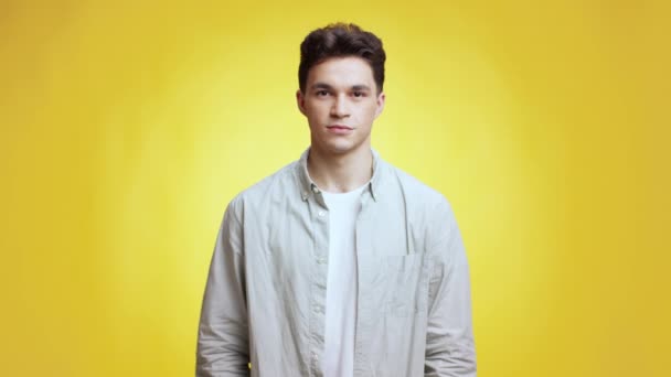 Its okey. Young positive man gesturing OK and winking to camera, approving idea, smiling to camera, yellow background - Footage, Video