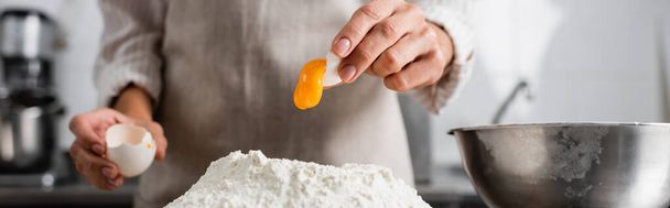 Cropped view of chef pouring egg yolk on flour in kitchen, banner  - Foto, Bild