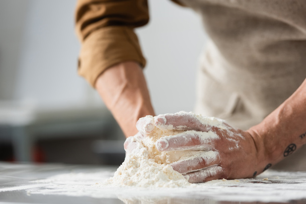 Cropped view of blurred chef making dough on kitchen table  - Fotografie, Obrázek