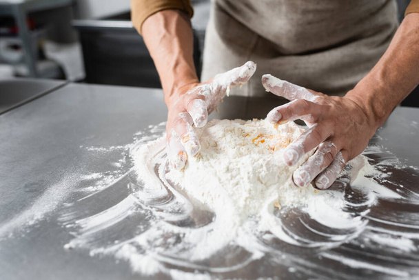 Cropped view of mature chef in apron making dough on kitchen table  - Fotografie, Obrázek