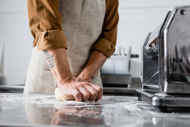 Cropped view of chef making dough near pasta maker machine on table in kitchen  - 写真・画像