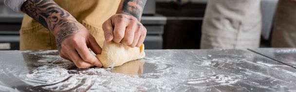 Cropped view of tattooed chef making dough near flour on kitchen table, banner  - Foto, Imagem
