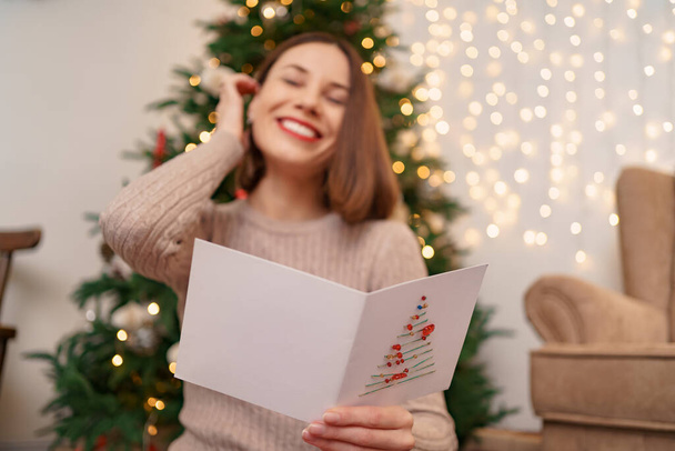 Schöne junge Frau liest eine Weihnachtsgrußkarte - Foto, Bild