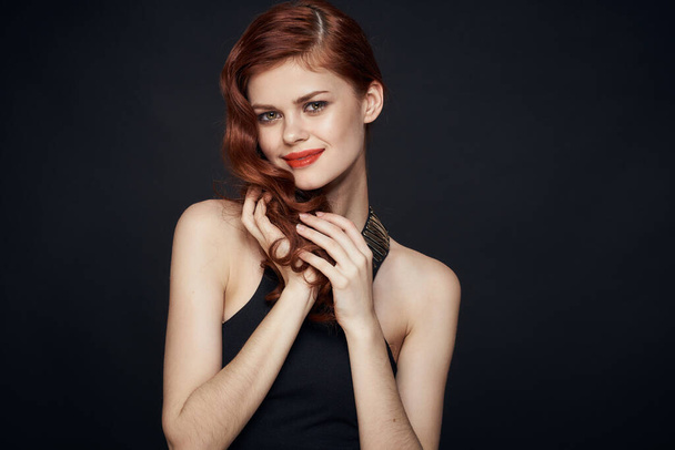 attractive red-haired woman in a black dress hairstyle dark background - Foto, Imagen