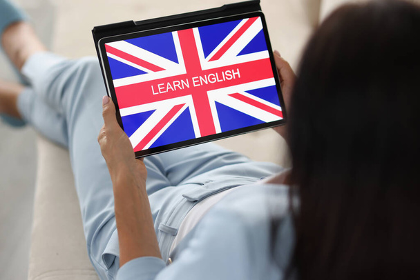 Donna imparare l'inglese da casa sul divano utilizzando dispositivo tablet - Foto, immagini