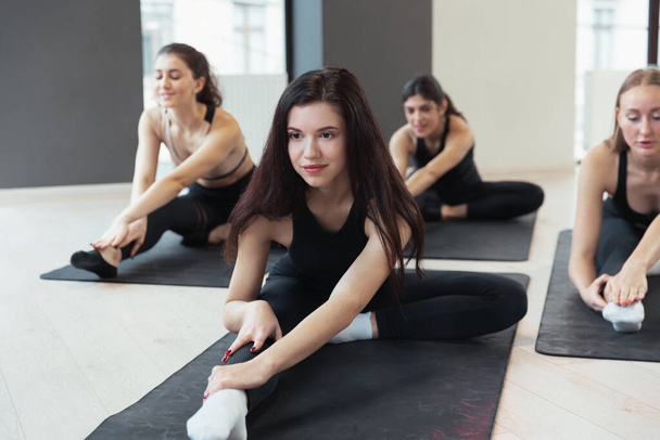Close-up young sportive women in sportswear doing yoga exercises on sports mats at yoga meditation center. Concept of healthy lifestyle, wellbeing - Photo, image