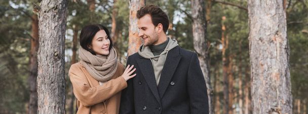 young and happy couple in autumn outfit looking at each other in park, banner - Photo, image