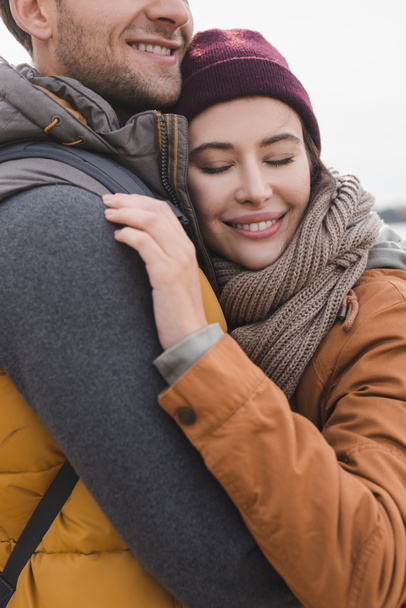 happy woman in autumn clothes hugging man while walking outdoors - Foto, imagen