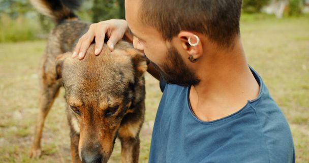 A young Indian guy petting a stray dog in a park - Valokuva, kuva