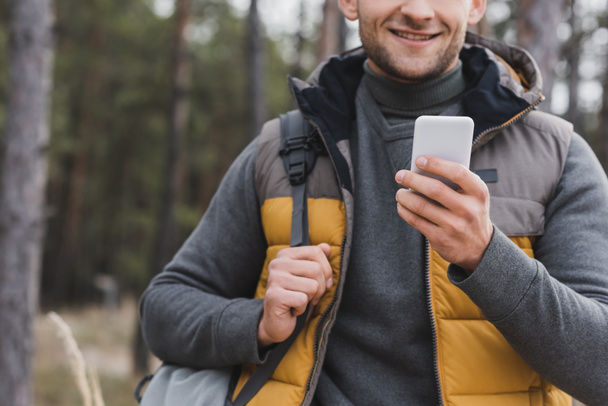 osittainen näkymä miehen reppu käyttäen älypuhelinta navigointiin metsässä - Valokuva, kuva