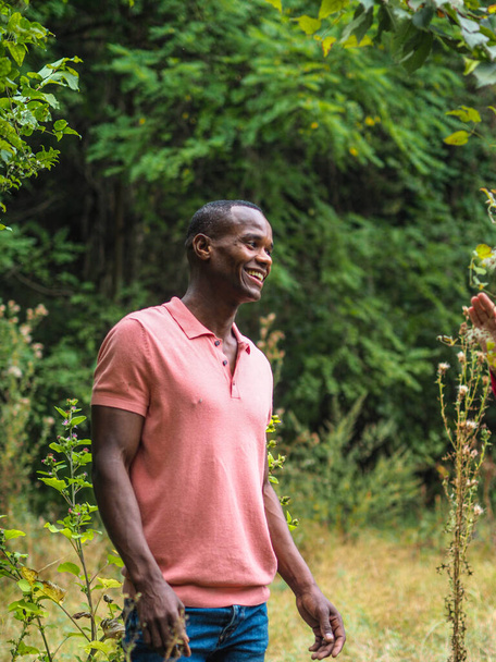 An African man from Italy in pink t-shirt smiling in a field - Photo, image