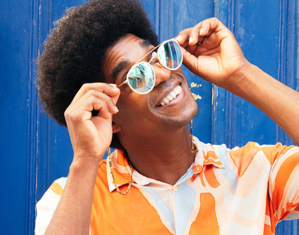 A black man with curly hair wearing fancy sunglasses outdoors - Zdjęcie, obraz