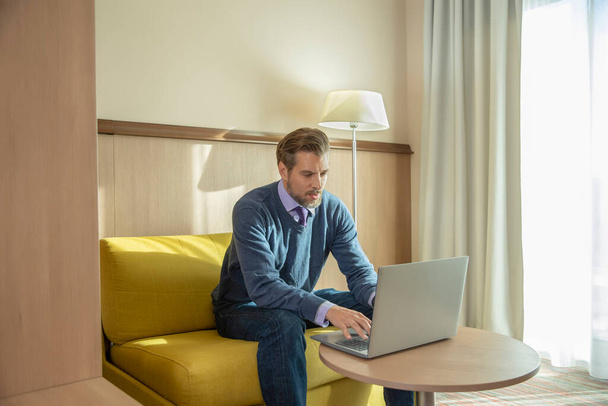 Handsome man with beard working on a notebook in hotel room - Foto, Imagem