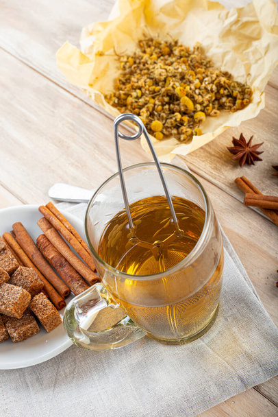 Hot chamomile tea made of wild flowers with a mesh ball tea infuser - Foto, Bild