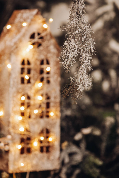 galho de árvore de Natal pendurado de cima com uma casa de brinquedo atrás - Foto, Imagem
