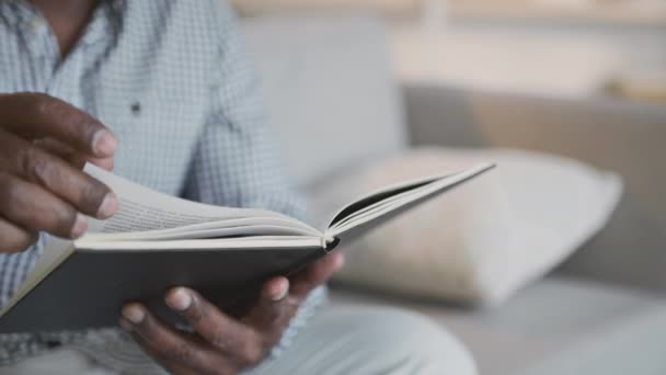 Beyin egzersizleri. Tanımlanamayan kıdemli Afrikalı Amerikalı adam kitap okuyor, evdeki kanepede dinleniyor, çekim takibi yapıyor. - Video, Çekim