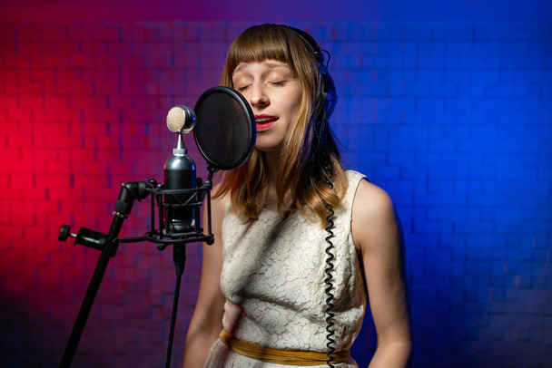 Singer woman in headphones performs song heartily. Microphone with pop filter - Foto, immagini