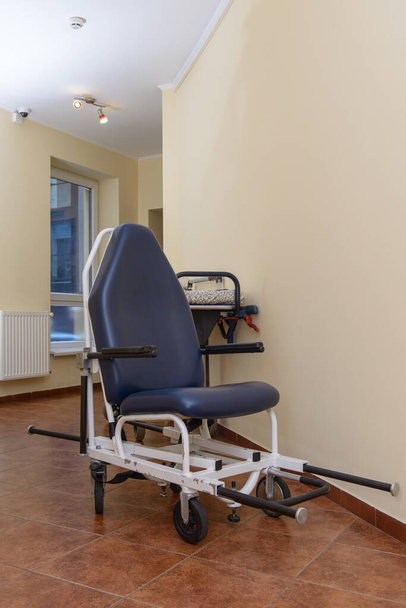 Fahrbarer und verstellbarer alter Krankenhausstuhl. Flur in der Klinik - Foto, Bild