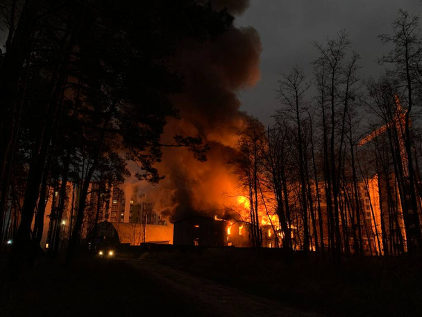 Geceleri bir konut binası yanıyor. Yüksek binaların olduğu bölgede büyük bir yangın çıktı. Konsept: yangın güvenliği, acil durum. - Fotoğraf, Görsel
