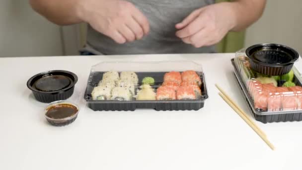 Koncepcja dostawy żywności: człowiek otwiera dostarczane pudełko z japońskim jedzeniem. Zabrać jedzenie. - Materiał filmowy, wideo