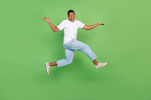 Koko kehon profiilin sivukuva nuori afrikkalainen kaveri hypätä ylös ymmällään eristetty yli vihreä väri tausta. - Valokuva, kuva