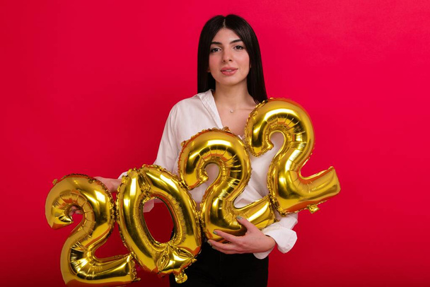 Una giovane donna con una camicia bianca detiene i numeri del prossimo nuovo anno 2022 - Foto, immagini